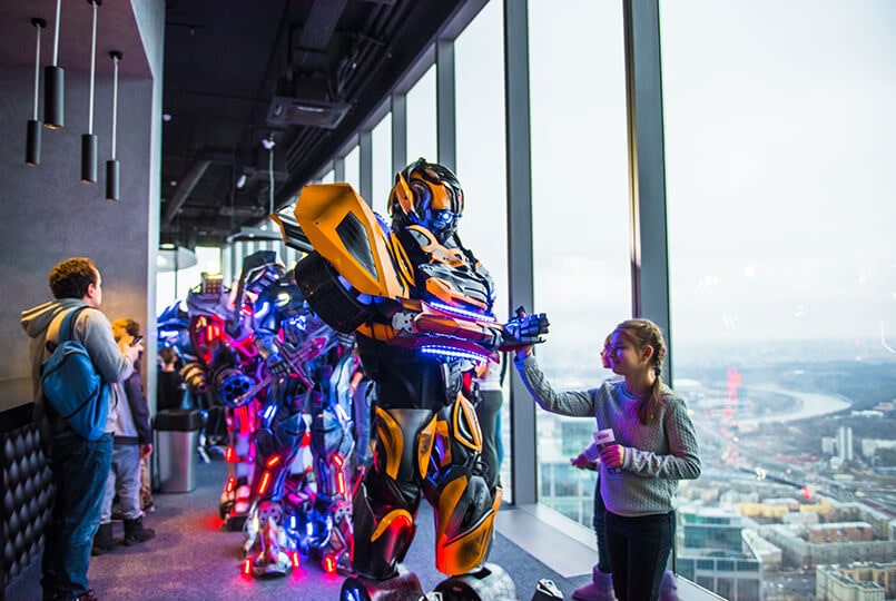Желтый робот трансформер гуляет в Moscow City и приветствует детей
